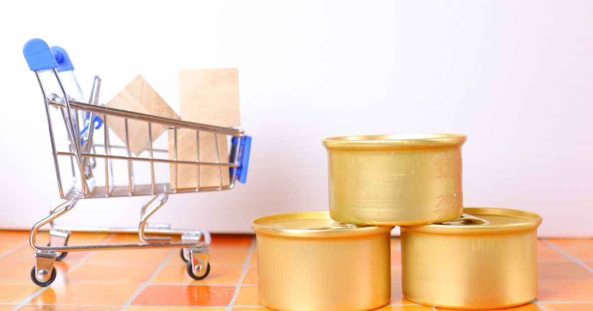 ミニカートと金色の缶詰が並ぶショッピングイメージ