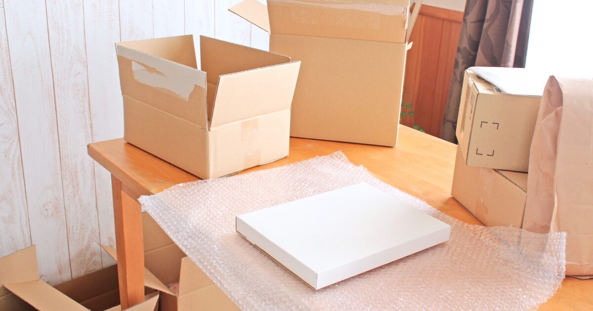 梱包作業中の段ボールと緩衝材と白い箱