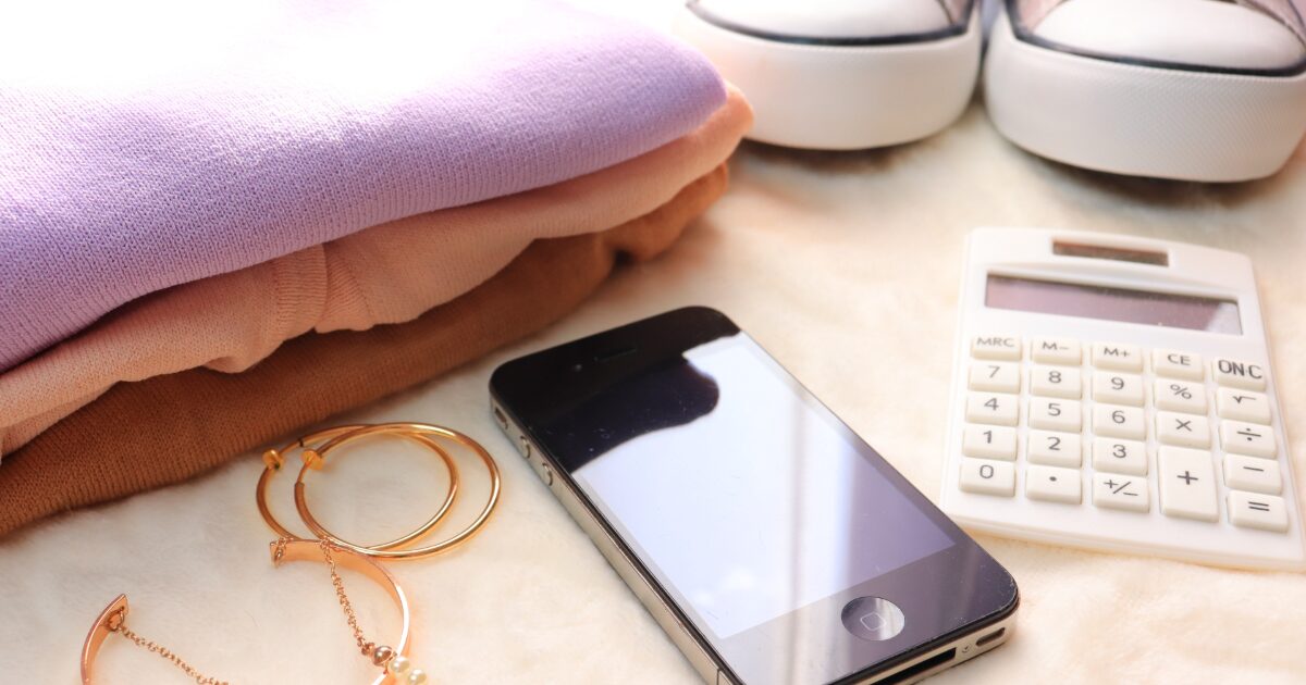 衣類とアクセサリーとスマートフォンが並ぶフリマ出品準備