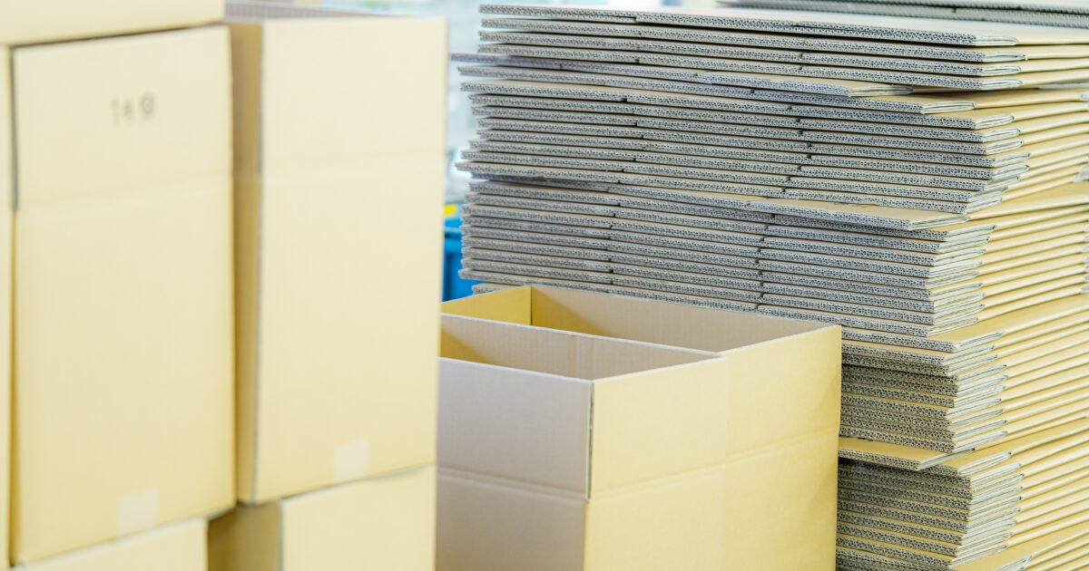 大量の段ボール箱と梱包資材が並ぶ倉庫内の様子