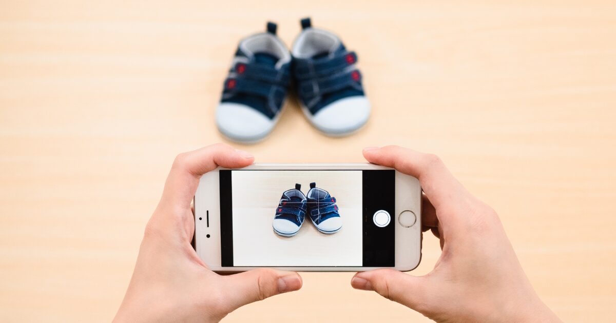 スマートフォンで子供用シューズを撮影する出品準備の様子